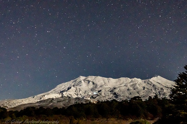 Mt Ruapehu from access Rd to Chateau with ski chalet lights on mountain and night shy behind - Night Sky - Graham Reichardt 