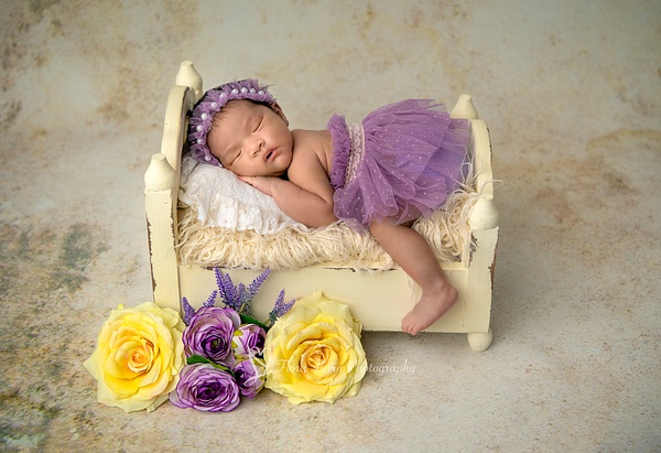 Newborn baby girl on a bed_Flora_Levin - Flora Levin Photography