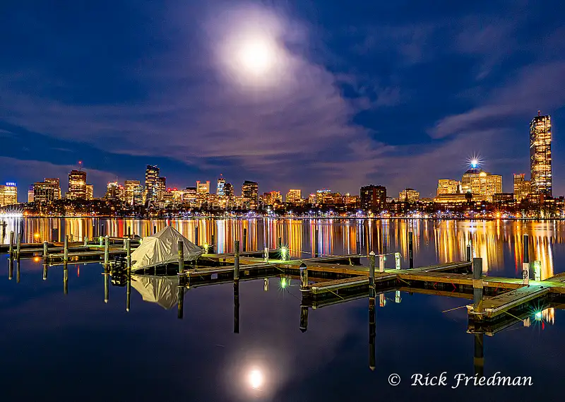 Reflections of the lights of Boston in  Charles River , seen through the dock from the Cambridge side by Rick Friedman