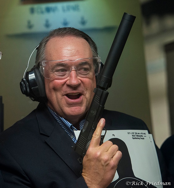 Former Governor, talk show host  Mike Huckabee holding  large gun  campaigning  for president in New Hampshire by Rick Fri - Politics - Rick Friedman Photography