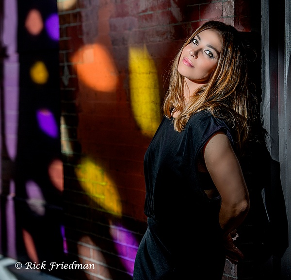 Model in black outside with colors projected on a fence in Boston by Rick Friedman - Rick Friedman Photography