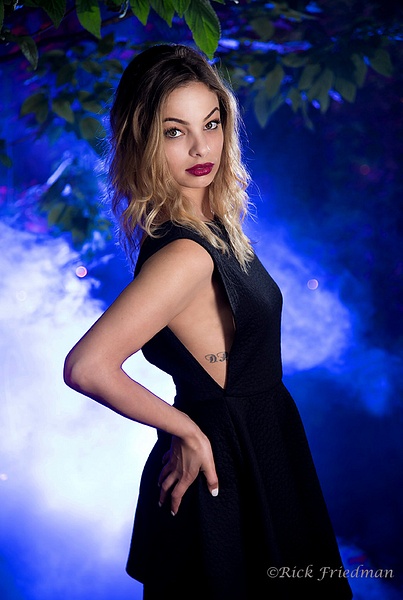 Model in black dress posing with blue light and smoke by Rick Friedman - Rick Friedman Photography 
