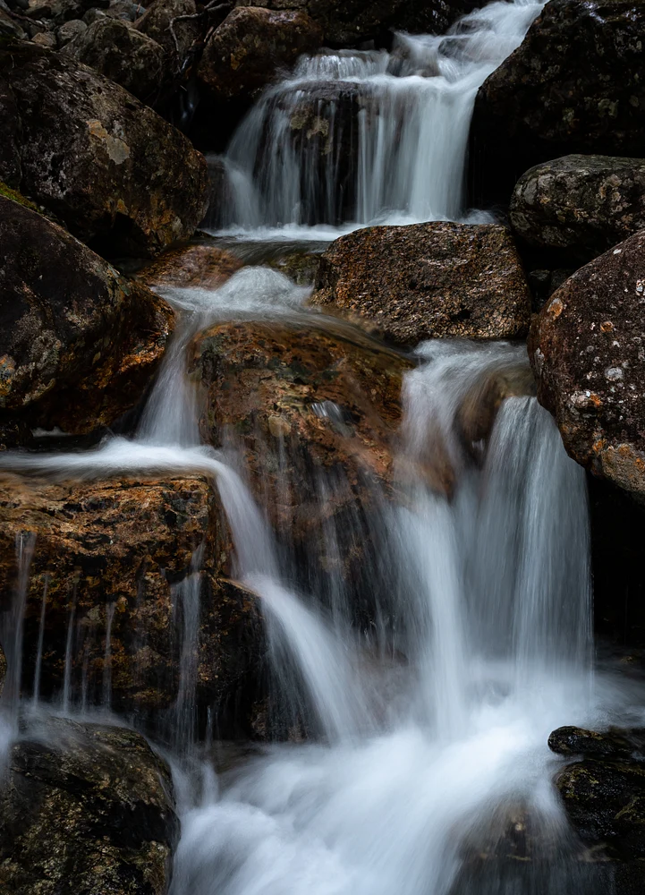 A close-up view of Troymsfossen waterfall cascading over rocks, creating a serene and tranquil natural scene.