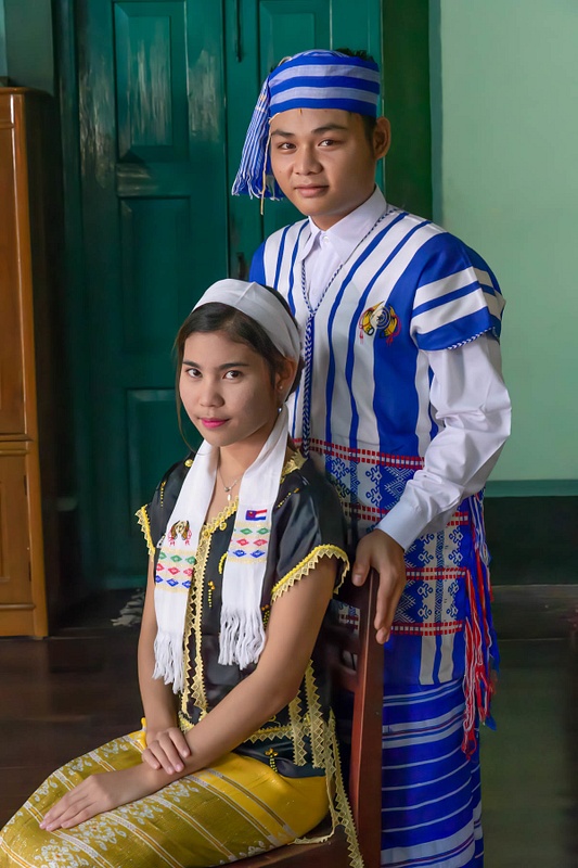 A couple in traditional dress poses for a portrait in Myanmar