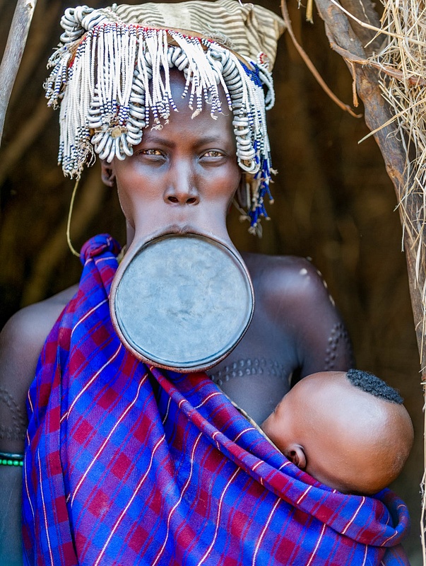A woman of the Mursi tribe wearing a clay lip plate and her baby, southern Ethiopia
