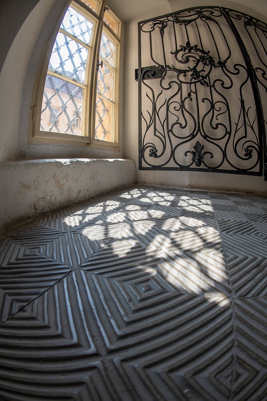 Patterns of light and shadow on the floor at the bottom of the grand staircase of the Libeň Chateau