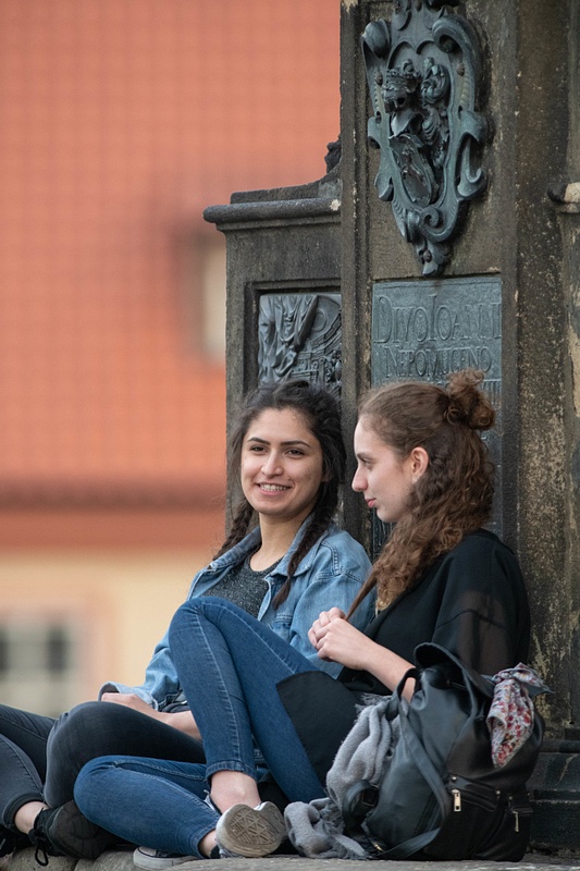 Friends talking at the pedestal of the Statue Of Saint John Of Nepomuk.