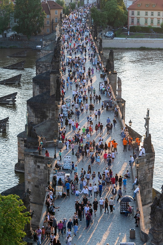 Golden shafts of the setting sun running through the crowd on the Charles Bridge.