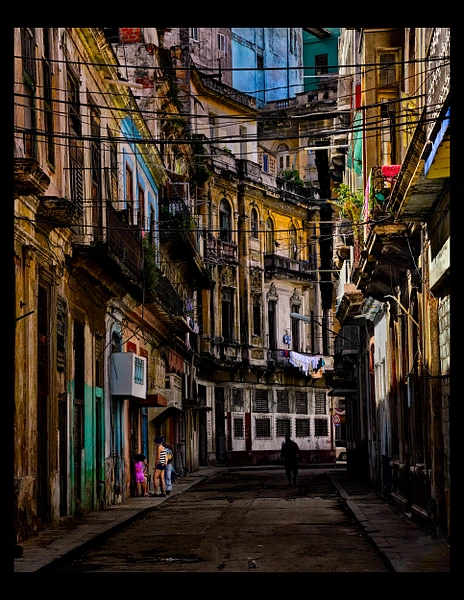 Narrow alleyway in Havana featuring colorful buildings and laundry.