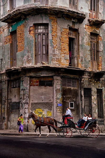 Horse-drawn carriage passing a historic building in Havana, Cuba.