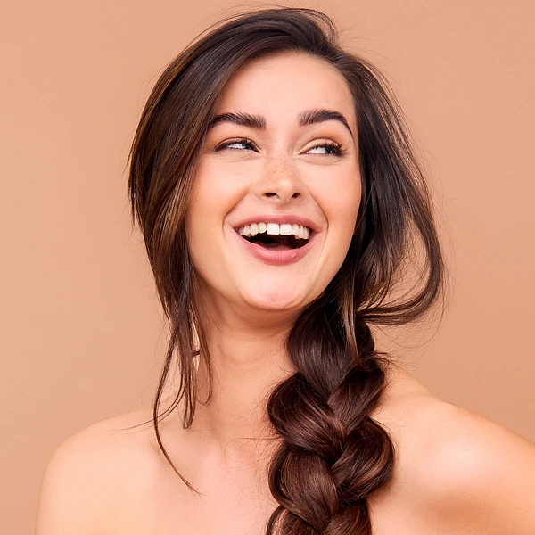 A  woman with braided hair and a joyful smile against a warm background.