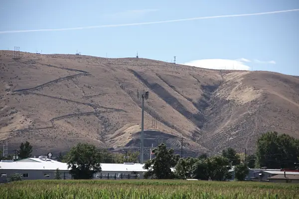 A dry, eroded hill looms over fertile, irrigated farm...