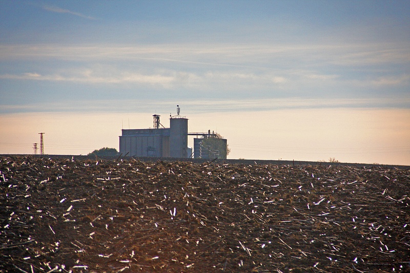 A grain storage complex towers over harvested fields