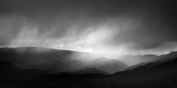 Black-and-white landscape near Camp Verde, Arizona, with storm clouds and rays of light across the hills.