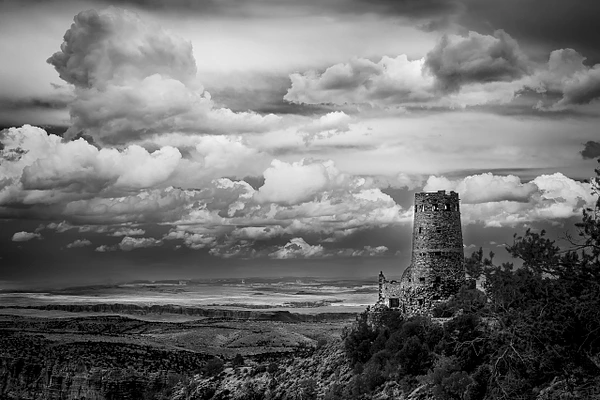 Black-and-white photograph of the Desert View Watchtower standing at the edge of the Grand Canyon.