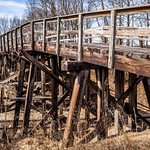 2018 An old wooden vehicle trestle over a rail line closed off to vehicle traffic.